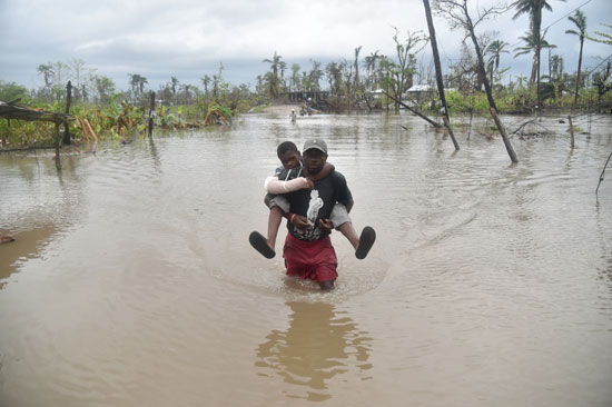 شخص يحمل طفلا للعبور به بركة مياه تجمعت نتيجة للأمطار الغزيرة